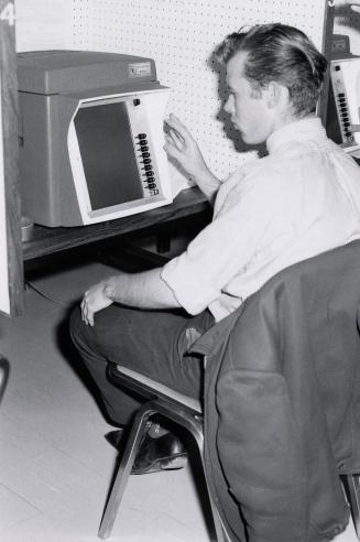 Picture of a person at a library carrel using a piece of equipment. 