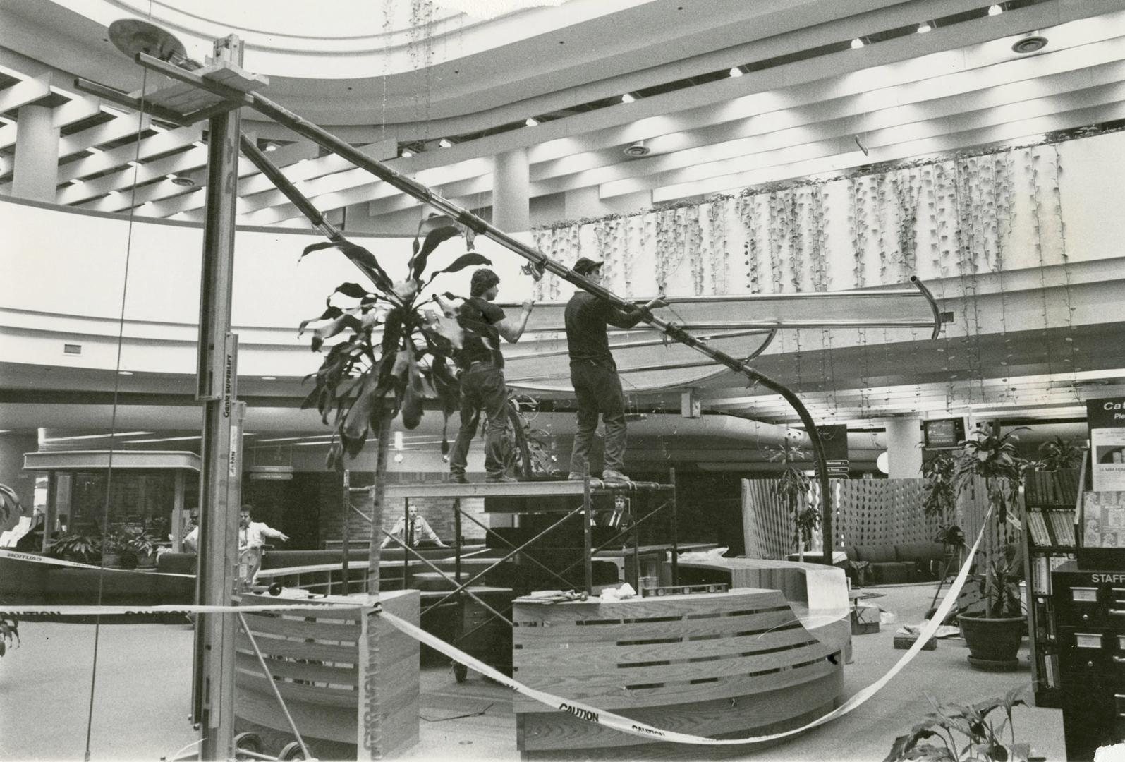 Picture of two men doing construction of round information desk in library with balconies in ba…