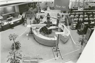 Picture of two men doing construction of round information desk in library with balconies in ba…
