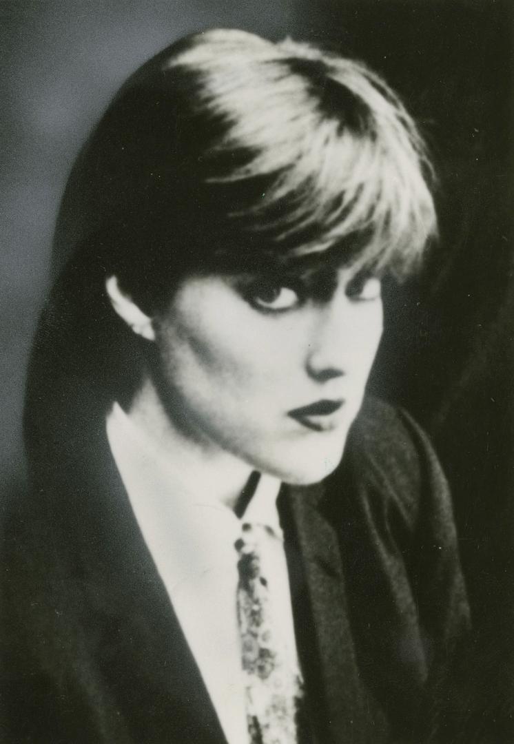 3/4 profile head and shoulders of young woman in blazer, shirt and tie. 