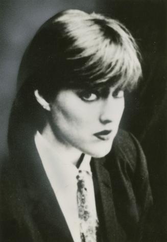 3/4 profile head and shoulders of young woman in blazer, shirt and tie. 