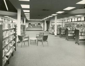 Picture of library interior showing sixties style chairs, shelving and service desk. 