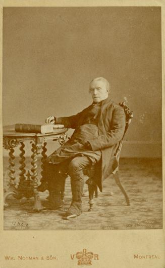 Man sitting in chair next to a table with a couple books