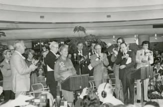 Picture of several people standing in front of podiums and some clapping for woman speaker. 