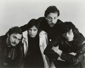 Huddled together against a white background, a man, a woman and two men in casual attire. Men w…