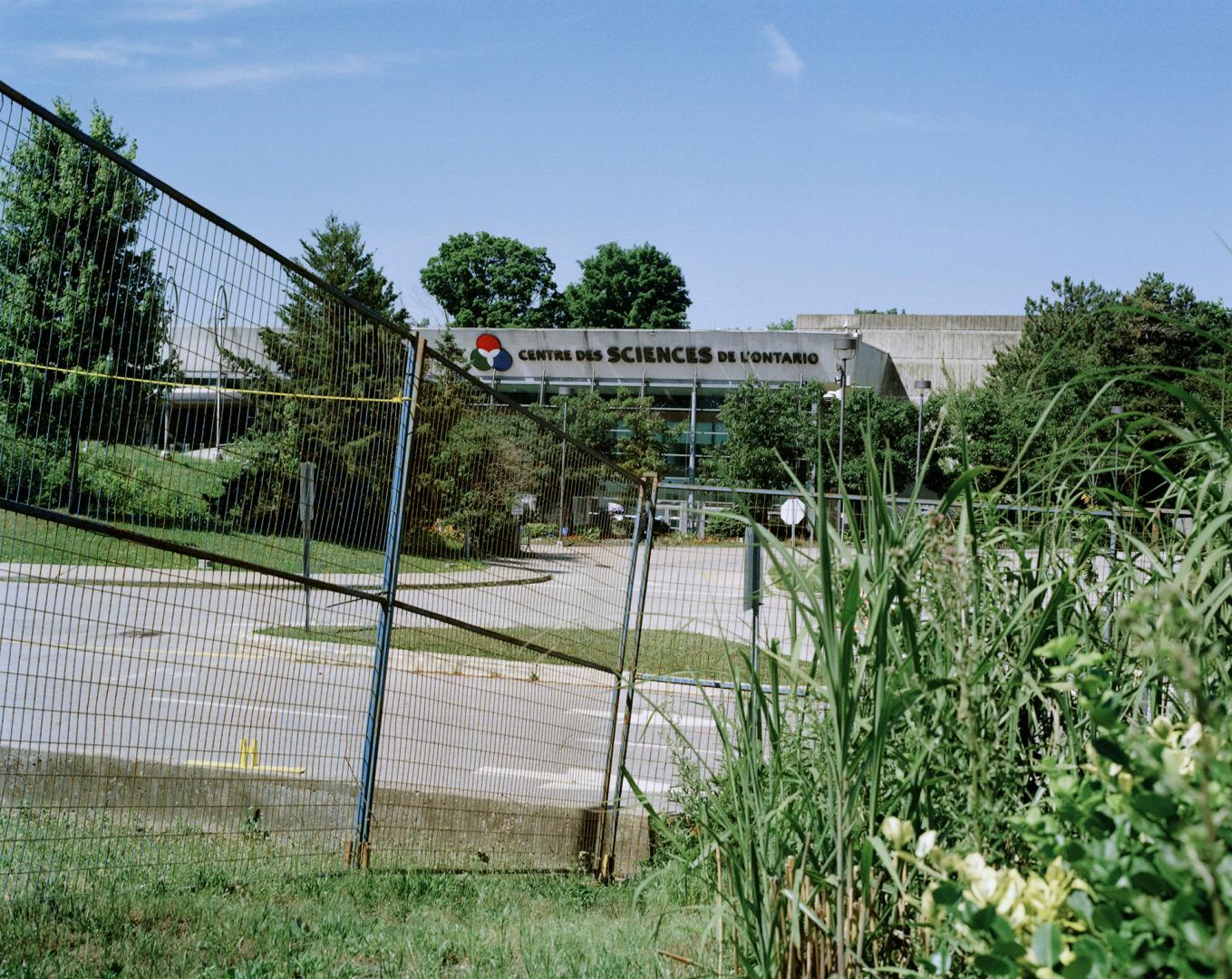Building in background surrounded by evergreens reads "Centre des sciences de l'Ontario" with f…