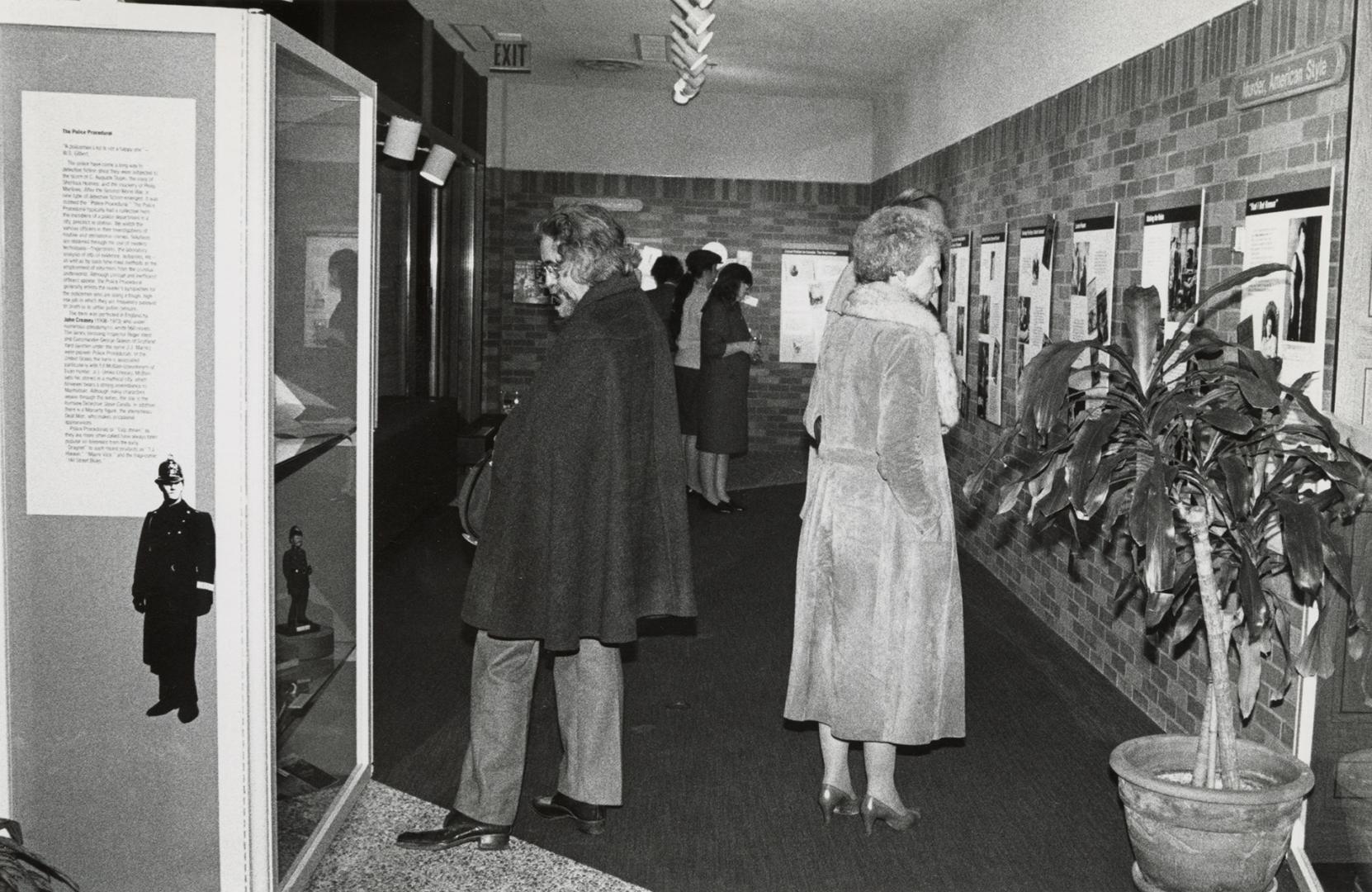A man and a woman stand back to back in a gallery showcasing materials from the Toronto Public …