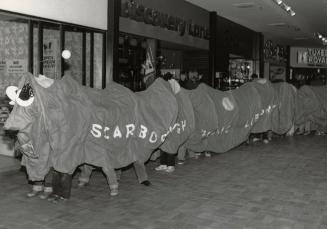 Picture of long fabric bookworm walking with children inside holding it up. 
