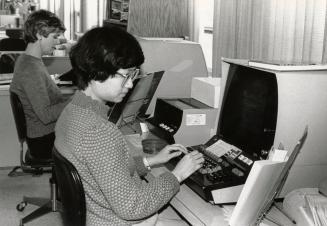 Picture of two women working at large computer terminals. 