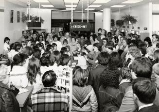 Picture of large crowd of people inside a library. 