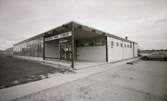 Picture of a 1960's library building with several cars parked out front. 
