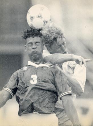 Two young men butt side of heads as they both try to head butt the ball just above them. Both f…