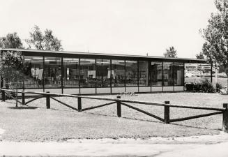 Picture of the exterior of a 1960's one story library building with glass windows all across th…