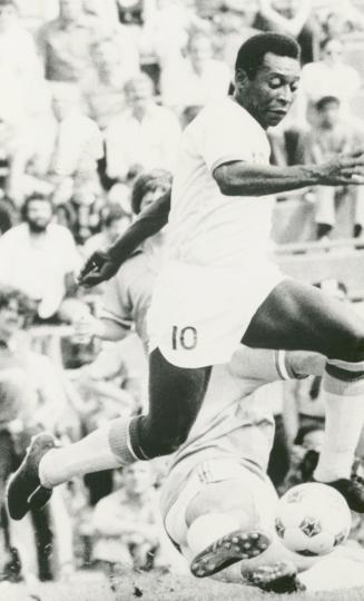 Man in Soccer gear running with the ball beside his front foot. Man near him tumbles onto the f…