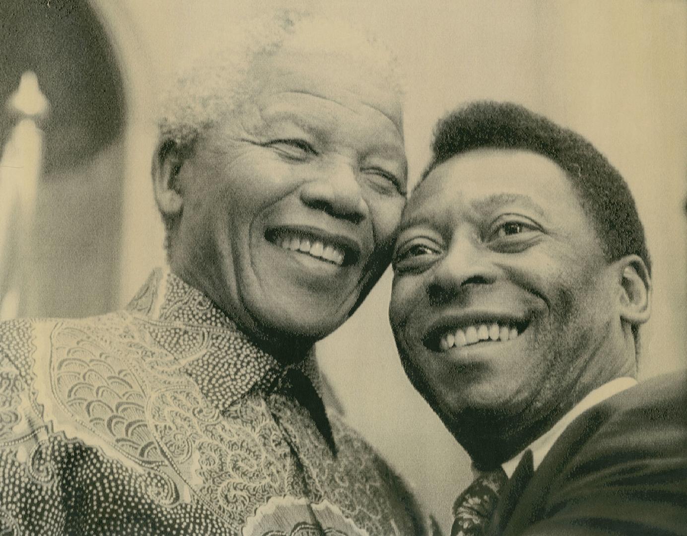Two men smiling head to head. Pele in suit, Mandela in patterned shirt. 