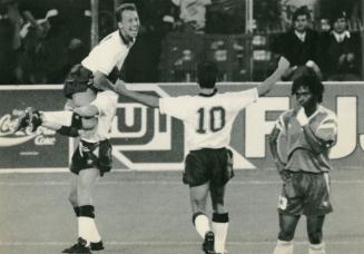 On the soccer field near the boards, one plays lifts another over his head holding his legs aga…
