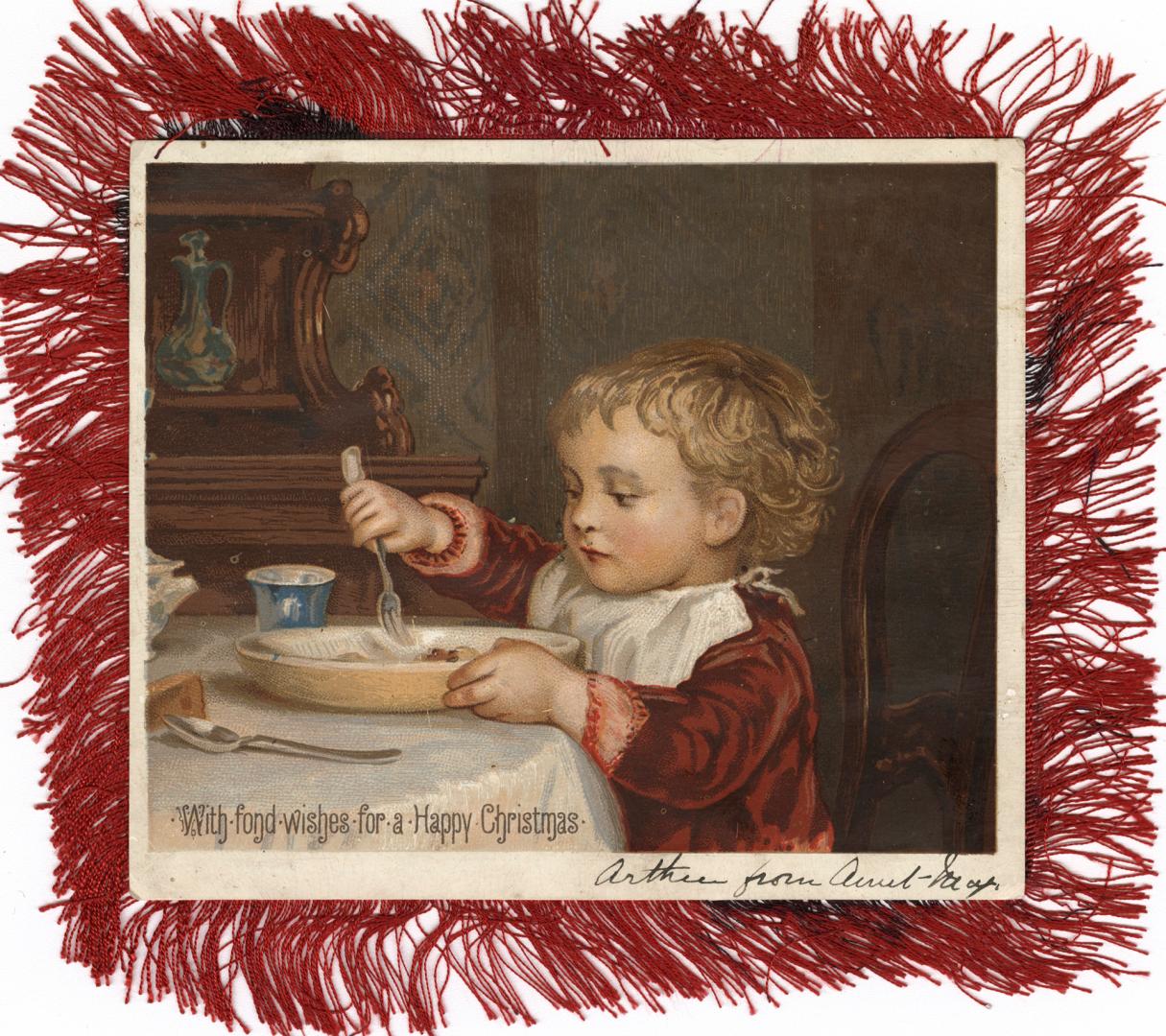 The card pictures a child sitting at a table with a plate of food. The card has a red silk frin…
