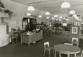 Picture of inside a library showing shelves, tables and chairs. 