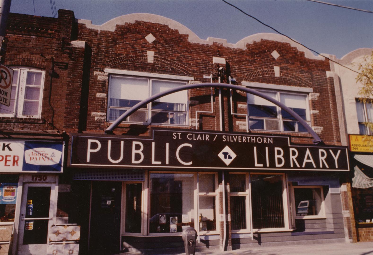 Picture of double storefront library with large sign above the building reading public library.…