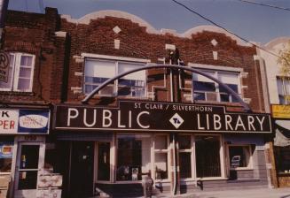 Picture of double storefront library with large sign above the building reading public library.…