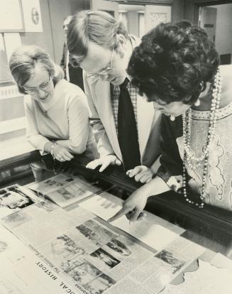 Picture of three people leaning over a display case looking at the display. 