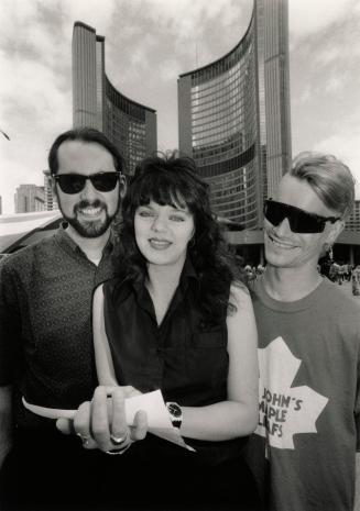 Young man in sunglasses, girl in black shift and man in sunglasses and Maple Leafs T-shirt stan…