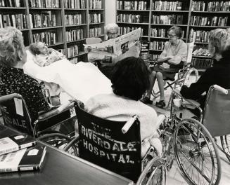 Picture of several seniors sitting in a circle in a library room with some in wheelchairs and o…