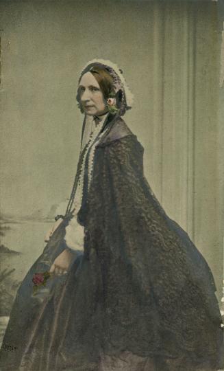 Hand-coloured photograph of a 19th-century woman seated for a 45-degree profile portrait wearin…