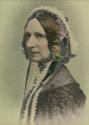 Hand-coloured photograph of a 19th-century woman seated for a 45-degree profile portrait wearin…