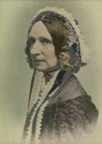 Hand-coloured photograph of a 19th-century woman seated for a 45-degree profile portrait wearin…