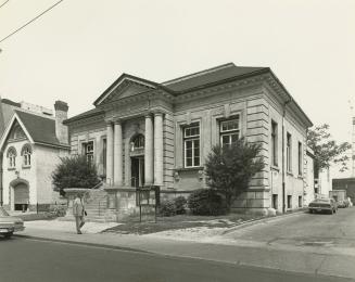 Picture of a one story stone library building with four pillars and portico. 