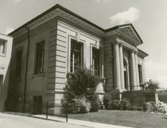 Picture of a one story stone library building with four pillars and portico. 