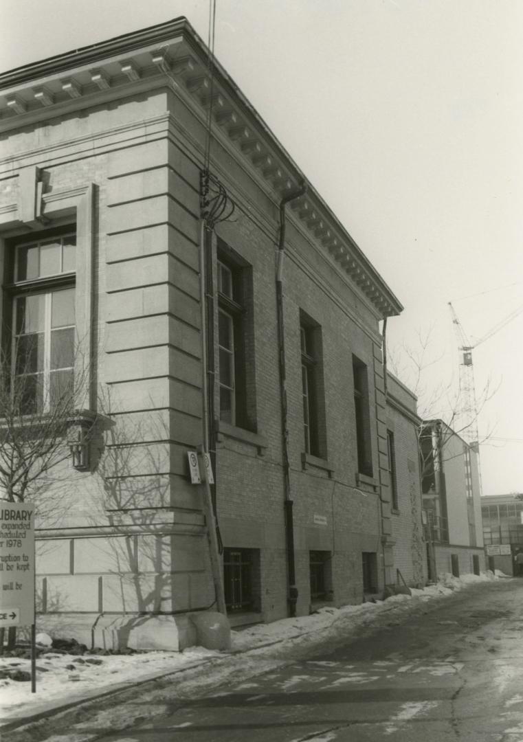 Side view of a one story stone library building with four pillars and portico. 