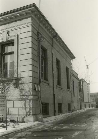 Side view of a one story stone library building with four pillars and portico. 