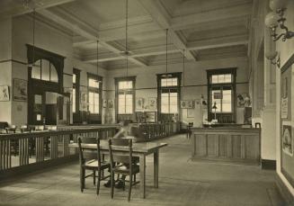 Picture of a large room in a library tall windows, ornate ceiling and reading areas separated b…