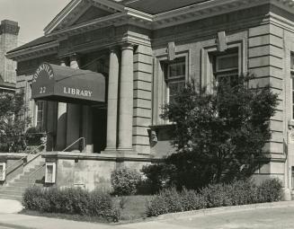 Picture of one storey brick and stone library with four pillars, portico and awning over front …