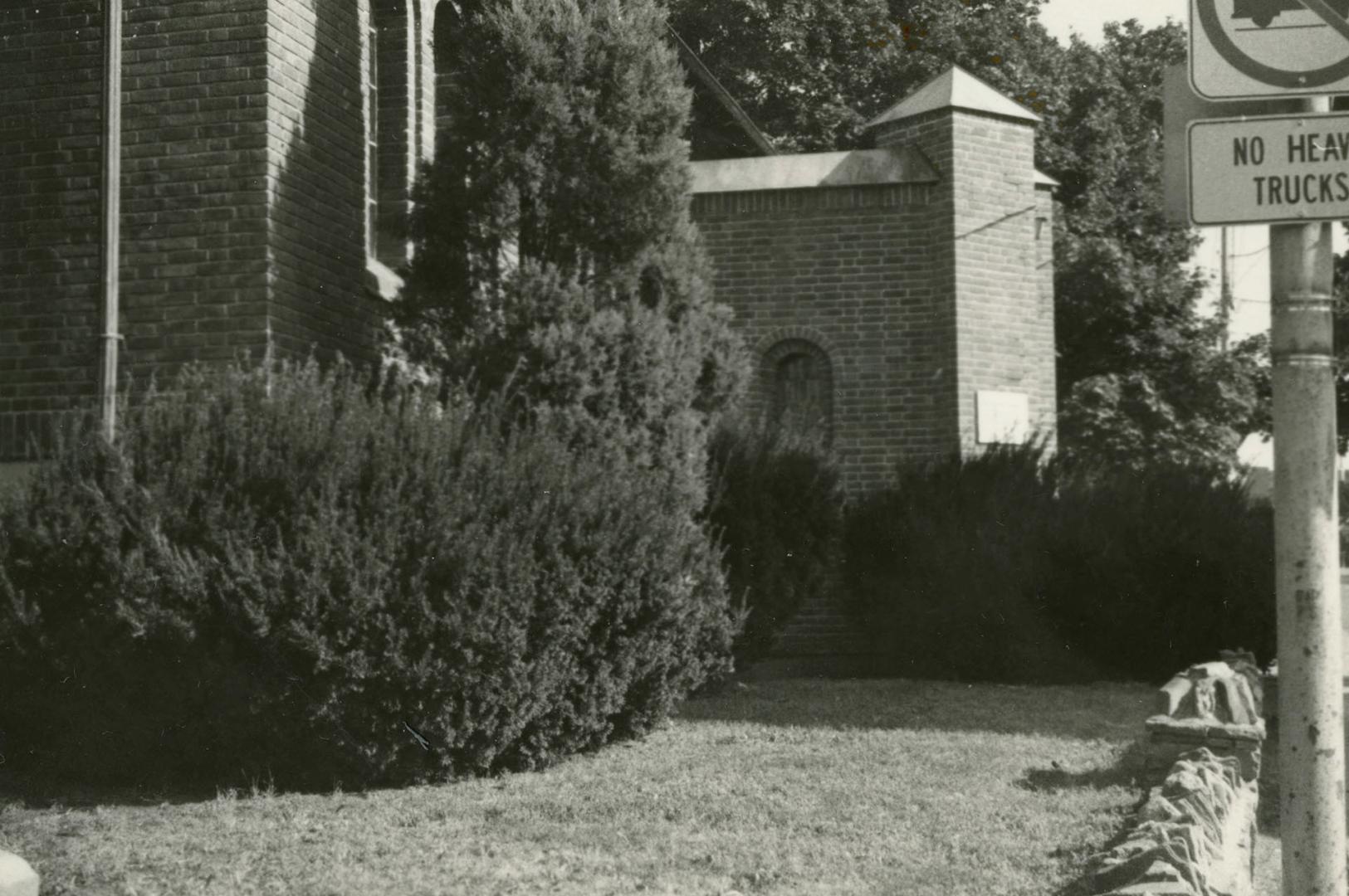 View of part of brick library building with lawn and bushes in front. 
