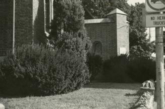 View of part of brick library building with lawn and bushes in front. 