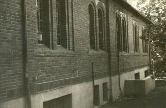 Side view of brick library building showing several pairs of arched windows. 