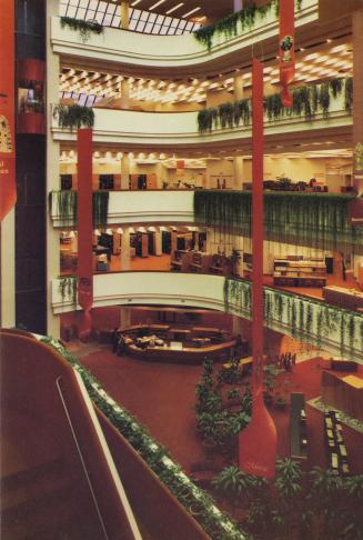 Picture of the interior of a multi storey library with balconies, plants and banners. 