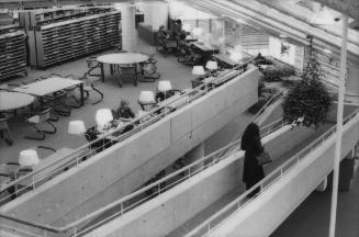 Picture of interior of a library showing ramp to second floor and tables and shelves. 