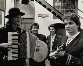 4 men in suits and white shirts in alleyway with sign behind them, Gadler's Mews. From left wit…