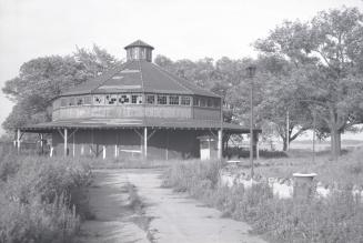 Photograph of an abandoned wooden building housing a merry-go-round. 