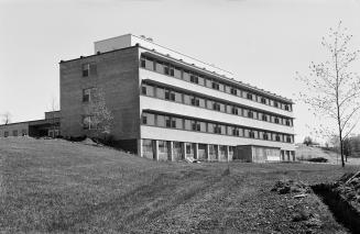 Photograph of a three storey hospital building with lawn in front. 