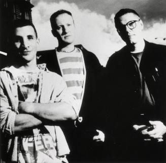 Three men against a cloudy sky, wearing t-shirts and bomber jackets, all have short hair.