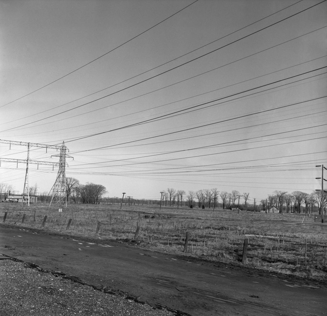 Photograph of road and field with hydro wires overhead. 