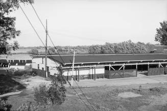 Photograph of a long boathouse with water in the background.