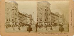 Picture of a street with pedestrians on the sidewalk and crossing and buildings on one side of …