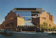 Picture of the exterior of a multi storey red brick library building with glass covered entranc…