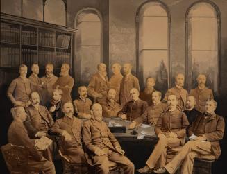 Composite sepia photograph of numerous adults posed around a table in a formal interior, some s…